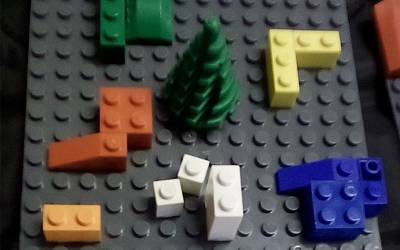a grey lego board with different coloured blocks spaced unevenly around with a tree in the middle