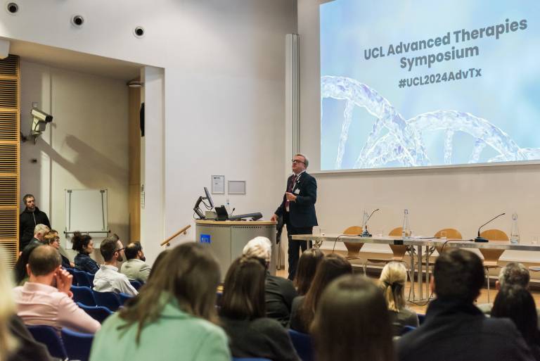 A photo with Prof. Geraint Rees on stage against a screen showing text of UCL Advanced Therapies Symposium.