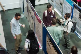 A photo showing some people discussing in front of the poster boards