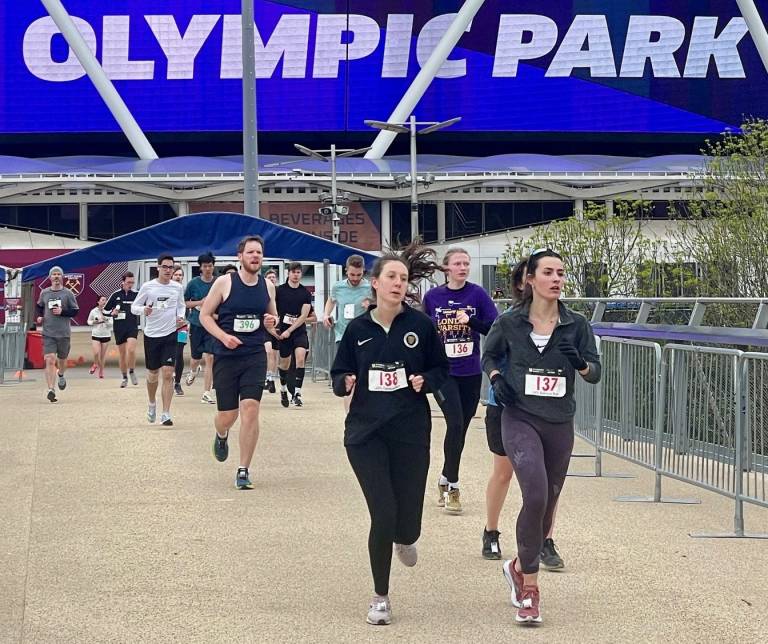A group of runners heading towards the camera with the words 'Olympic Park' on the stadium behind them