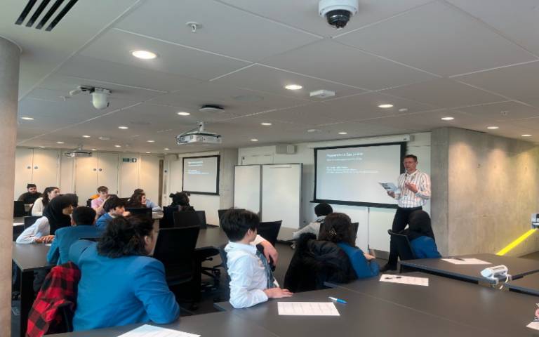 Professor Ben Campkin beside a screen with students from the UCL Academy school in front ot him in a UCL East campus seminar room