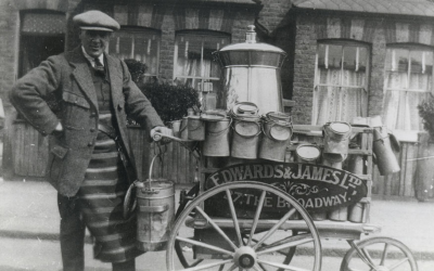 Old picture of man delivering milk on a cart.