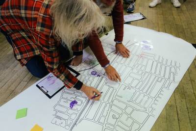 Two men knelt over a large map of Forest Gate on the floor, annotating it.