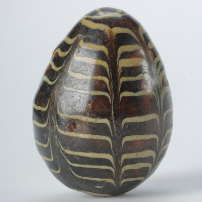 photo of a brown egg with white wavy lines across the front. The egg is placed on a white surface.