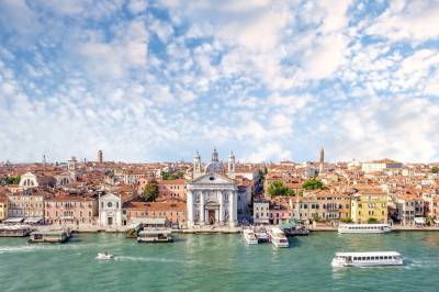 Landscape Photograph of Venice, a city sat behind the water made of up old buildings against a blue sky with clouds
