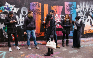 People stand in front of a graffiti wall talking and laughing.