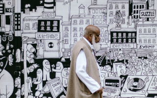 Man walking past a cartoon mural wall. 
