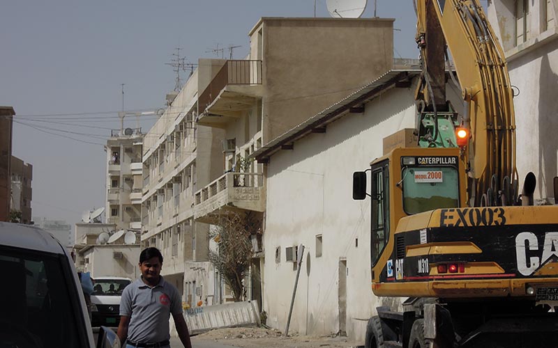 A man walks down a street in Doha next to a construction vehicle
