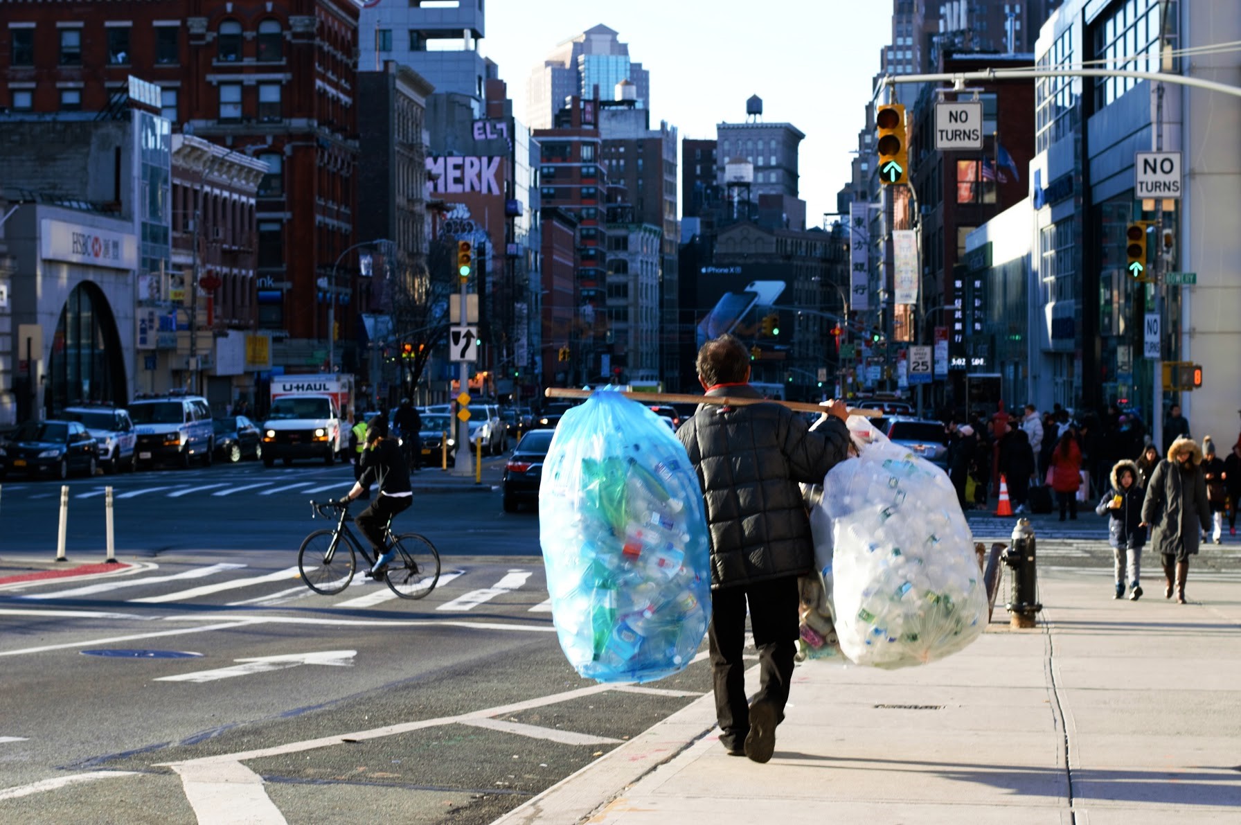 Photo of a man walking in New York with two huge bags full of waste plastic