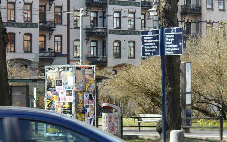 Street scene in Gothenburg with a car passing and posters stuck to a piece of street furniture