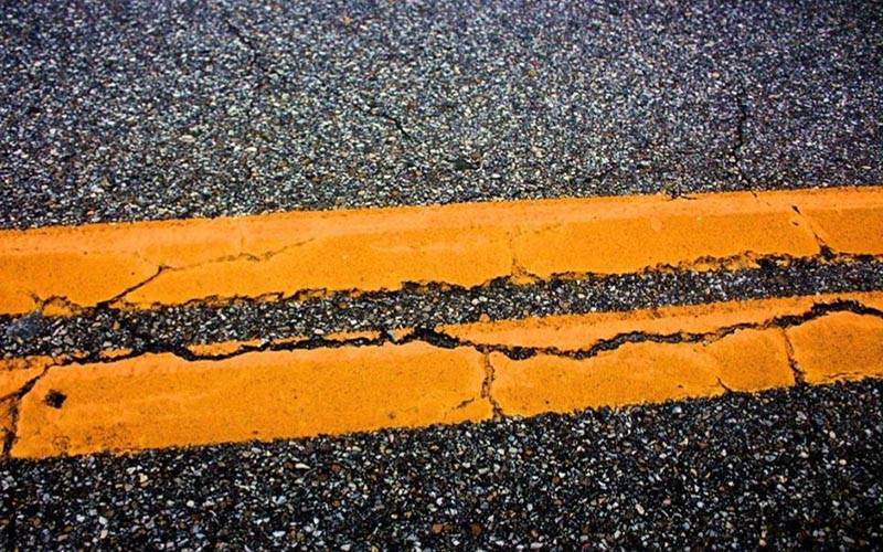 Image of cracked orange parking restriction markings on a road