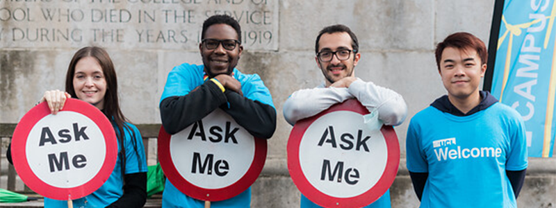 Picture of students holding up a 'Ask me' sign