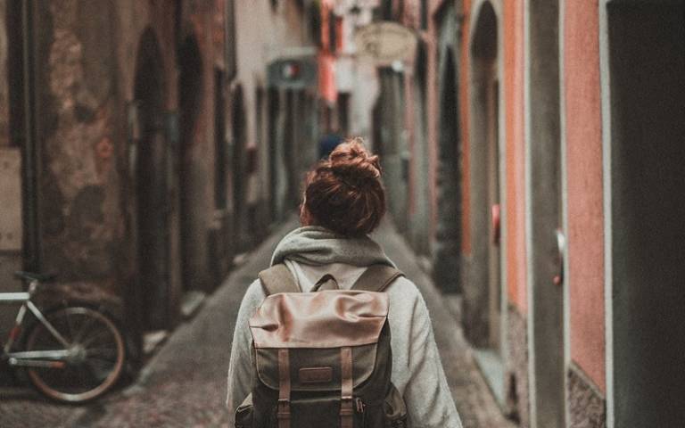 Woman walking down the street with backpack. Credit: Timo Stern / Unsplash